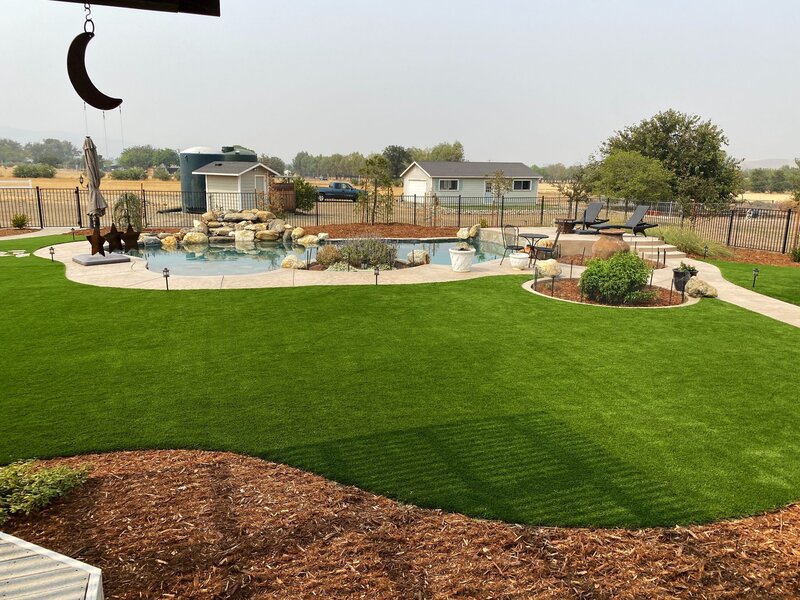 Lush artificial grass lawn installed around a garden pool